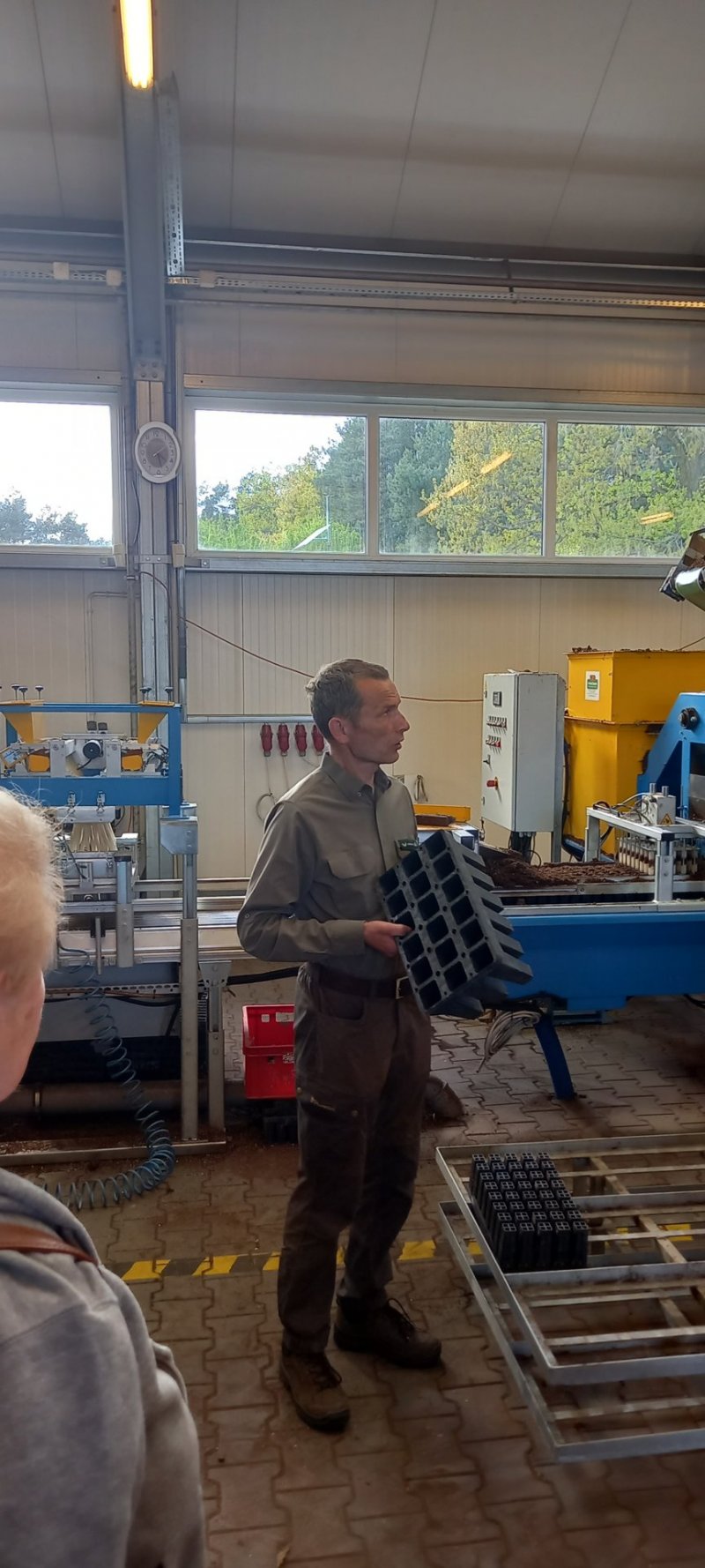 Leśniczy Wojtek Stec omawia linię produkcyjną nasion w kontenery